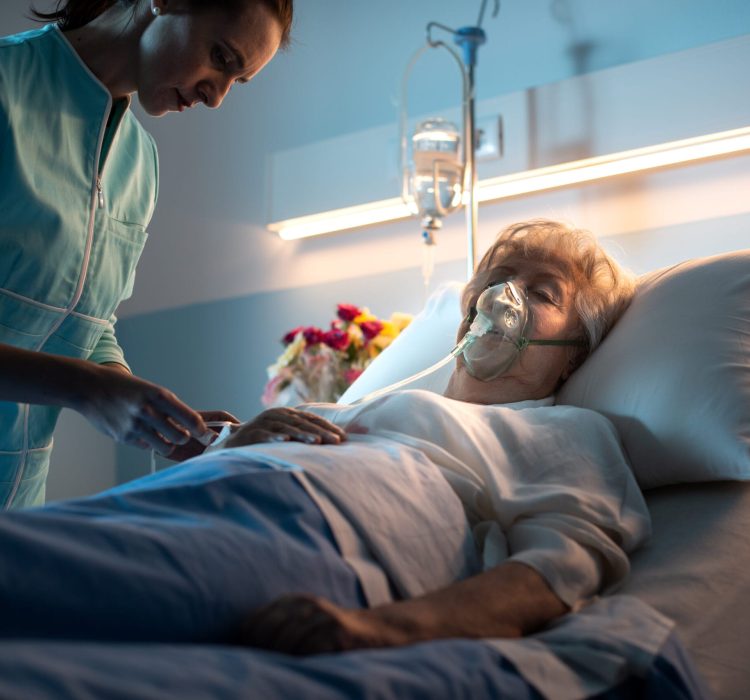 Professional nurse checking a senior woman lying in bed at the hospital